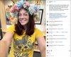 A person wearing glasses and a large floral crown, smiling while taking a selfie in a yellow Gary the Cat t-shirt with a printed on demand graphic.