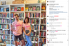 A man and a woman stand in a bookstore wearing matching pink books t-shirts that say MY JOB IS... BOOKS.
