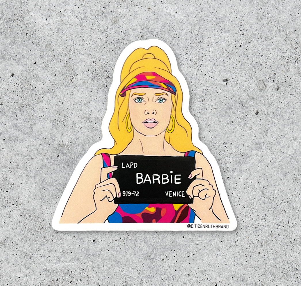 Waterproof vinyl sticker of a blonde woman in a colorful outfit holding an LAPD booking sign that reads BARBIE.