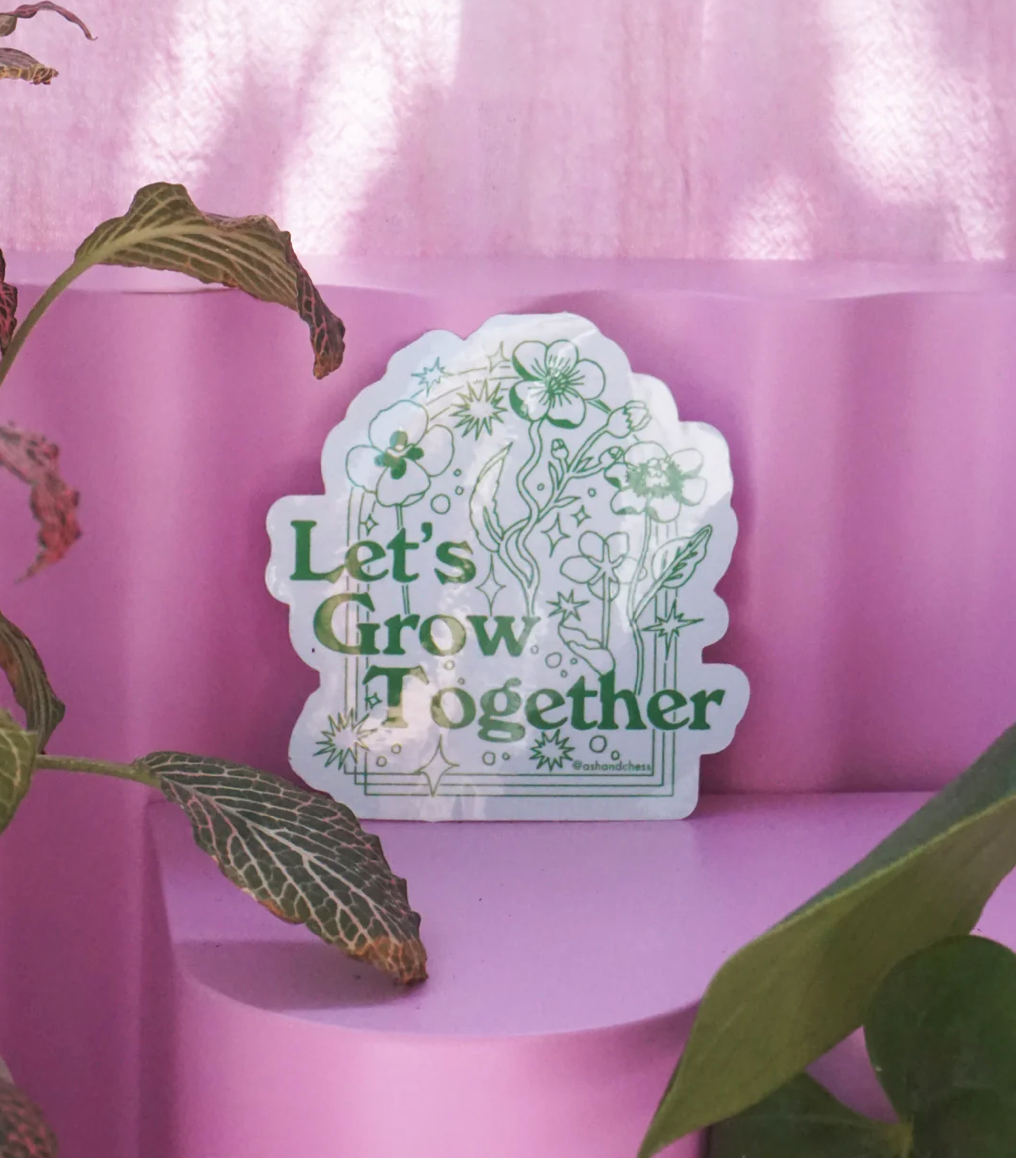 RAYGUN die-cut vinyl sticker that reads Lets Grow Together in green lettering, surrounded by illustrations of flowers and stars.