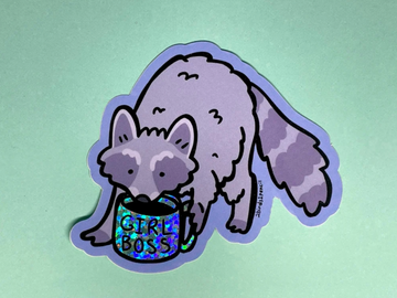 A cartoon raccoon holding a glittery, holographic mug that says GIRL BOSS on a waterproof vinyl sticker.