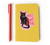 A yellow notebook featuring a high-quality sticker of a black cat wearing red devil horns with text that reads 100% that Bitch, placed next to a coral-colored pen.