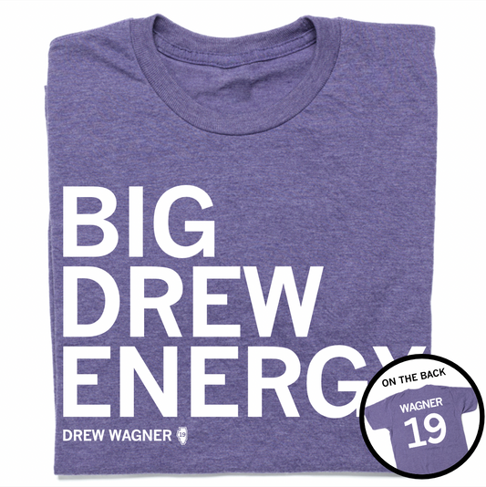 A folded heather purple t-shirt with left-aligned white text that reads "BIG DREW ENERGY" above smaller text that says, "DREW WAGNER" with a small outline of Illinois that has 19 in its center. A circle image in the bottom right corner shows the back of the t-shirt printed like a jersey with "WAGNER" above 19.