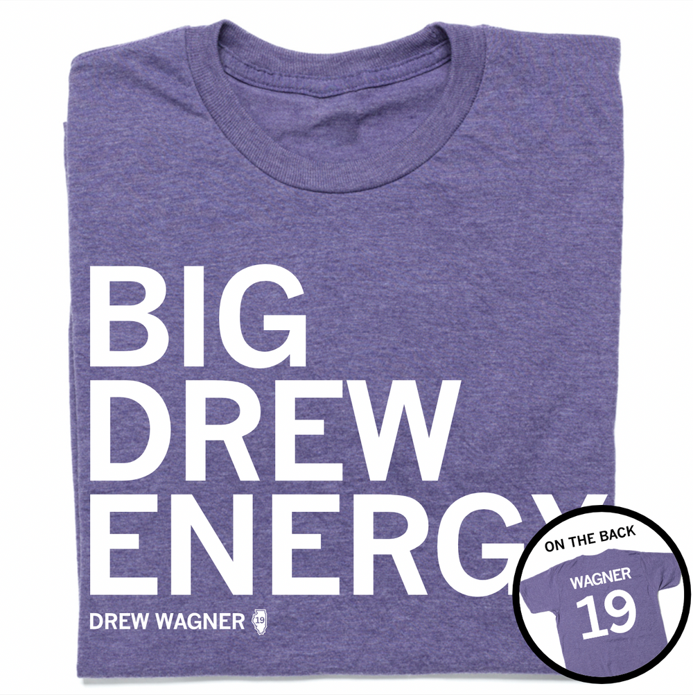 A folded heather purple t-shirt with left-aligned white text that reads "BIG DREW ENERGY" above smaller text that says, "DREW WAGNER" with a small outline of Illinois that has 19 in its center. A circle image in the bottom right corner shows the back of the t-shirt printed like a jersey with "WAGNER" above 19.