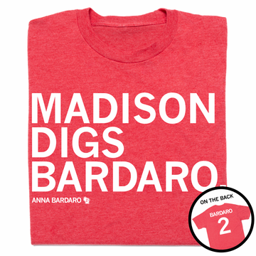 A folded heather red t-shirt with left-aligned white text that reads "Madison digs Bardaro" with smaller print below that says, "Anna Bardaro" with a small outline of Wisconsin to the right that has 2 in its center. In the bottom right corner a circular image is overlayed that shows the back of the shirt printed like a sports jersey.