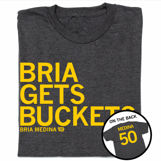 A folded heather charcoal t-shirt with left-aligned yellow ink print that reads "BRIA GETS BUCKETS" above "BRIA MEDINA" in smaller text with an outline of Iowa to the right. A circle image in the bottom right corner shows the back of the shirt laid out like a jersey with "MEDINA" printed above 50.