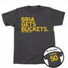 Short-sleeve charcoal t-shirt with left-aligned yellow ink print that reads "BRIA GETS BUCKETS" above "BRIA MEDINA" in smaller text with an outline of Iowa to the right. A circle image in the bottom right corner shows the back of the shirt laid out like a jersey with.
