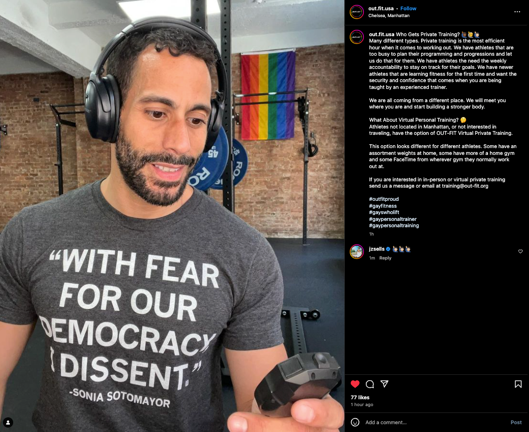 A man in headphones and an ACLU t-shirt quoting Justice Sonia Sotomayor looks down at a device in his hand while standing in a gym with a pride flag in the background.