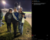 A marching band student in uniform stands between two women wearing matching charcoal t-shirts that read I cheer for the marching band at a nighttime football stadium.