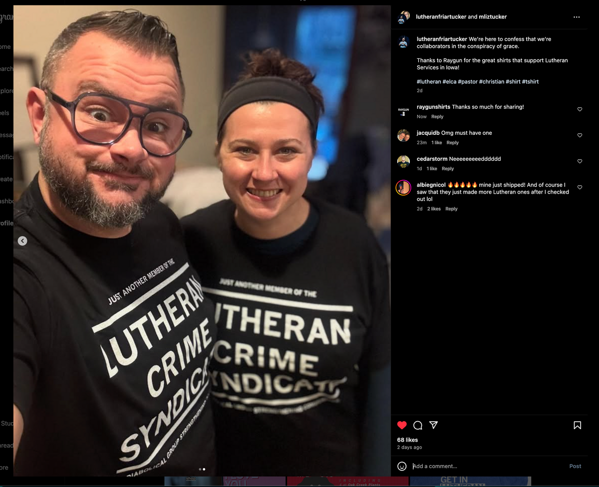 A man with glasses and a woman wearing a headband smile while wearing matching black union-made Lutheran Crime Syndicate t-shirts.