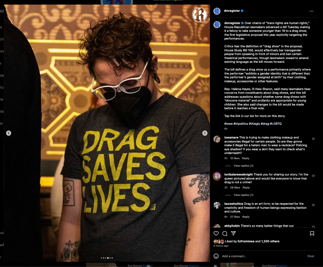 A person wearing glasses and a black face mask, dressed in a charcoal T-shirt that reads DRAG SAVES LIVES.
