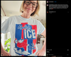 A person wears a light blue union made t-shirt featuring a cartoon of a character holding a child with the text Abolish ICE and Keep families together.