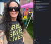 A woman with long dark hair wears sunglasses and a charcoal T-shirt that reads DRAG SAVES LIVES while taking a selfie at an outdoor market with a pink canopy in the background.