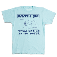Kids size pastel blue t-shirt with royal blue print. A doodle of a shark/cat hybrid is in the center with text above and below that reads "Watch Out. There is a Shat in the water." This shirt was designed by a kid taking part in a contest at our Cedar Rapids store.