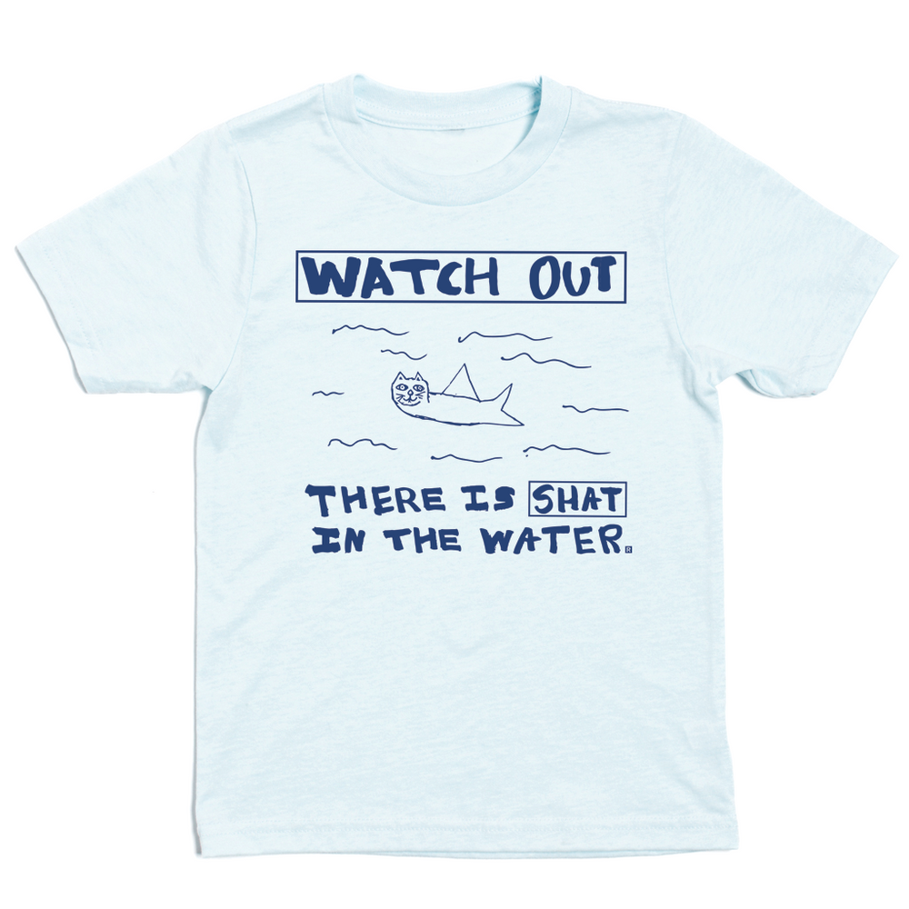 Kids sized pastel blue t-shirt with royal blue print. A doodle of a shark/cat hybrid is in the center with text above and below that reads "Watch Out. There is a Shat in the water." This shirt was designed by a kid taking part in a contest at our Cedar Rapids store.