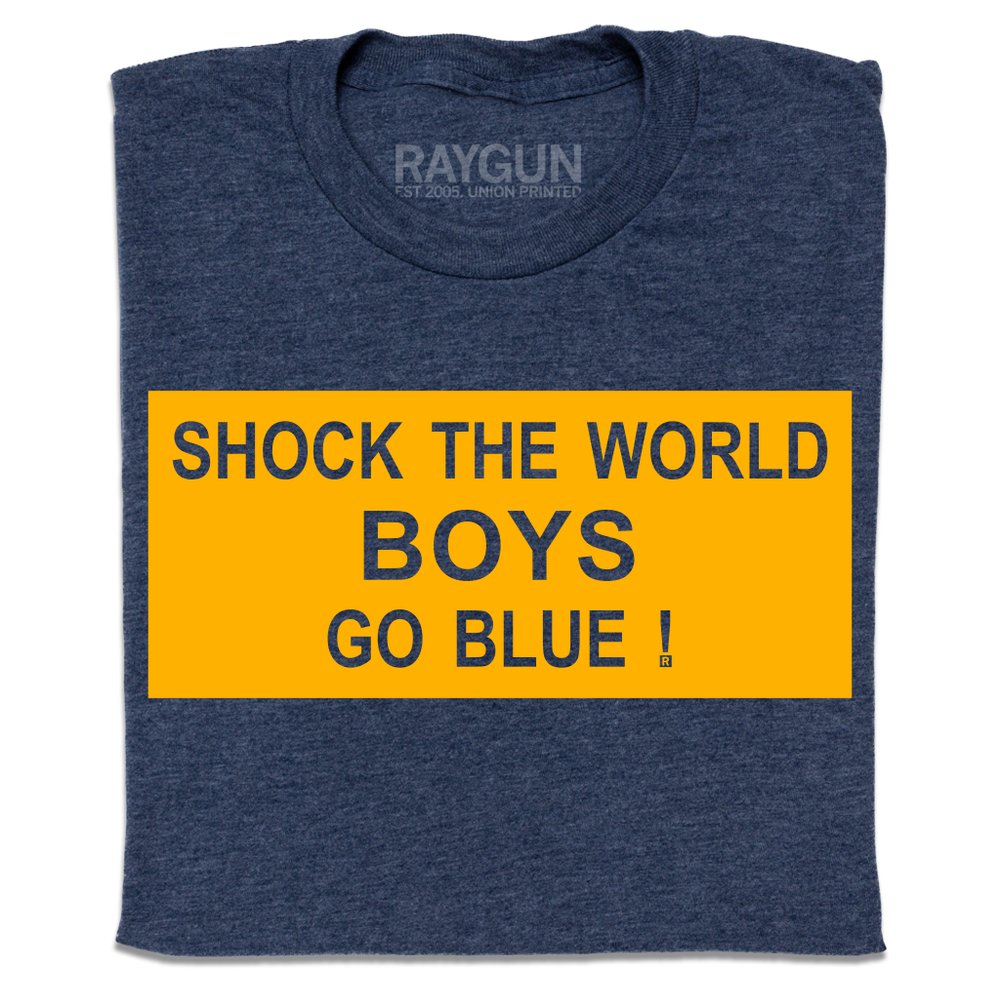 A folded heather navy t-shirt with a gold ink rectangle printed around the text "Shock the world
boys
Go blue!"