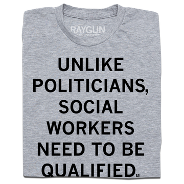 Folded heather grey t-shirt with black text that says, "Unlike politicians, social workers need to be qualified."