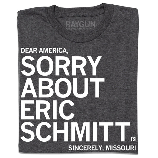 A folded heather charcoal t-shirt with white ink print that reads "Dear America, Sorry About Eric Schmitt. Sincerely, Missouri."