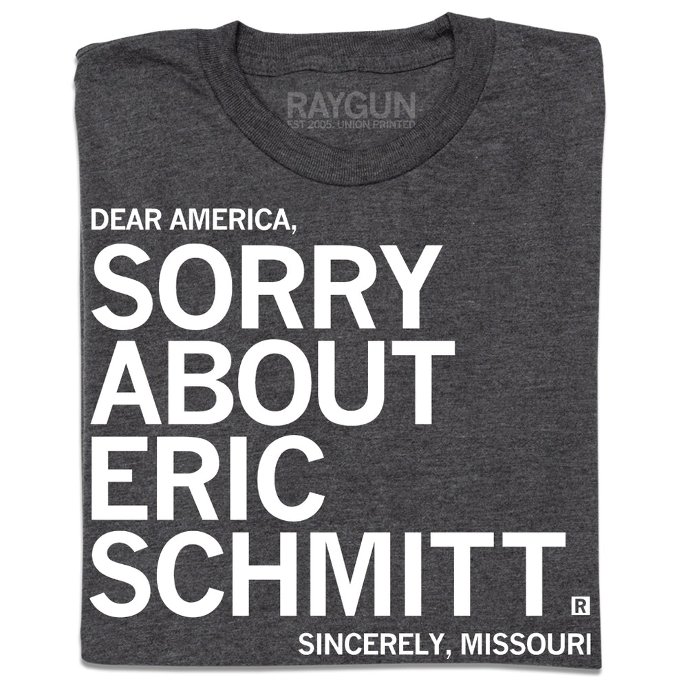 A folded heather charcoal t-shirt with white ink print that reads "Dear America, Sorry About Eric Schmitt. Sincerely, Missouri."