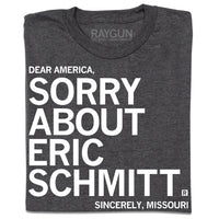 A folded heather charcoal t-shirt with white ink print that reads "Dear America, Sorry About Eric Schmitt. Sincerely, Missouri."