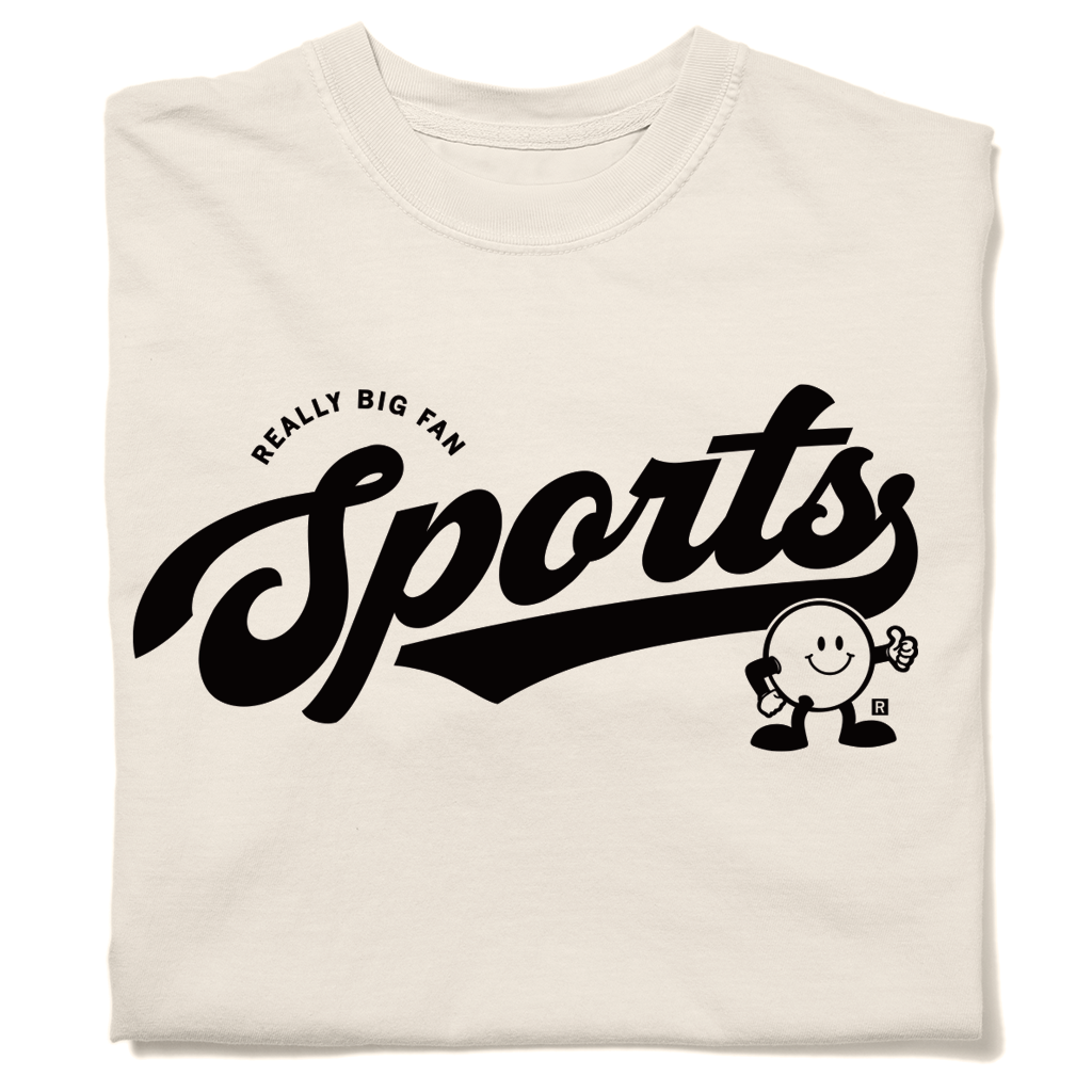Folded heavyweight ivory t-shirt with black ink in a vintage style text that says "Sports" across the chest. Small, curved text above says, "REALLY BIG FAN" and a circular cartoon character to the right if smiling and giving a thumbs up.