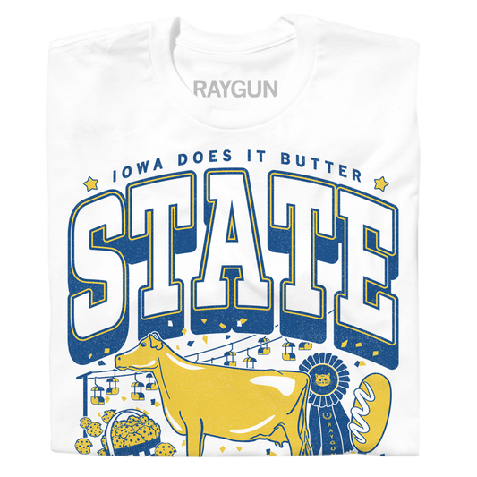 White RAYGUN t-shirt with a graphic reading IOWA DOES IT BUTTER featuring a yellow cow, a blue ribbon, a basket of cookies, and a buttered corncob inspired by the Iowa State Fair.