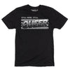 Black, sweatshop free t-shirt featuring the text STILL HERE, STILL QUEER printed above a checkered rectangle.