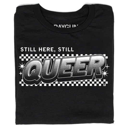 Black, union-made t-shirt featuring the text STILL HERE, STILL QUEER in a bold, comic-style font over a black and white checkerboard background.