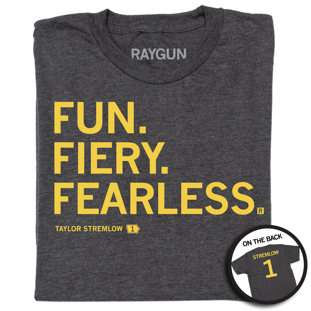 A folded heather charcoal shirt with gold left aligned in that reads "Fun. Fiery. Fearless. Taylor Stremlow 1" on the front and "Stremlow 1" printed on the back like a jersey.