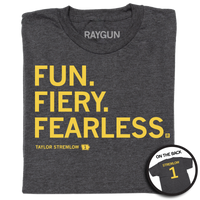 A folded heather charcoal shirt with gold left aligned in that reads "Fun. Fiery. Fearless. Taylor Stremlow 1" on the front and "Stremlow 1" printed on the back like a jersey.