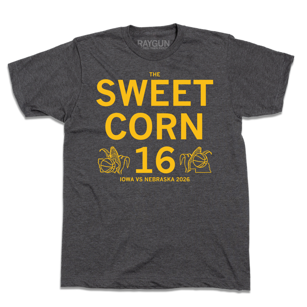 Heather black tee with centered gold ink text that reads "The Sweet Corn 16. Iowa vs Nebraska. 2026". In the lower left is an outline of Iowa with an ear of corn behind it and a basketball in front of it. In the Lower right is an outline of Nebraska with an ear of corn behind it and basketball in front of it.