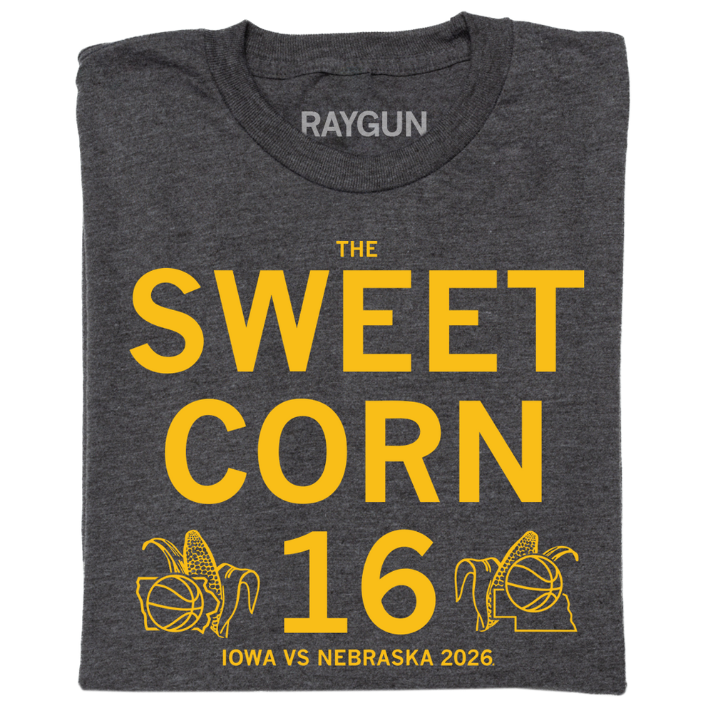 A folded charcoal t-shirt with centered gold ink text that reads "The Sweet Corn 16. Iowa vs Nebraska. 2026". In the lower left is an outline of Iowa with an ear of corn behind it and a basketball in front of it. In the Lower right is an outline of Nebraska with an ear of corn behind it and basketball in front of it.