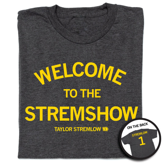 Charcoal RAYGUN t-shirt with yellow text reading WELCOME TO THE STREMSHOW and TAYLOR STREMLOW, with an inset showing the back of the shirt featuring the name STREMLOW and the number 1.