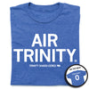 A folded heather royal blue t-shirt with all caps white text that says, "Air Trinity" in large text with small print below that reads "Trinity Shadd-Ceres." A small outline of Nebraska is printed to the right of her name with the number 0 in it. A small, circle image in the bottom right shows the back print. The back of the shirt is laid out like a jersey with her last name over her number.