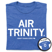 A folded heather royal blue t-shirt with all caps white text that says, "Air Trinity" in large text with small print below that reads "Trinity Shadd-Ceres." A small outline of Nebraska is printed to the right of her name with the number 0 in it. A small, circle image in the bottom right shows the back print. The back of the shirt is laid out like a jersey with her last name over her number.