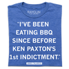 A folded heather blue shirt with white text that reads ""I've been eating BBQ since before Ken Paxton's 1st indictment." - James Talarico"
