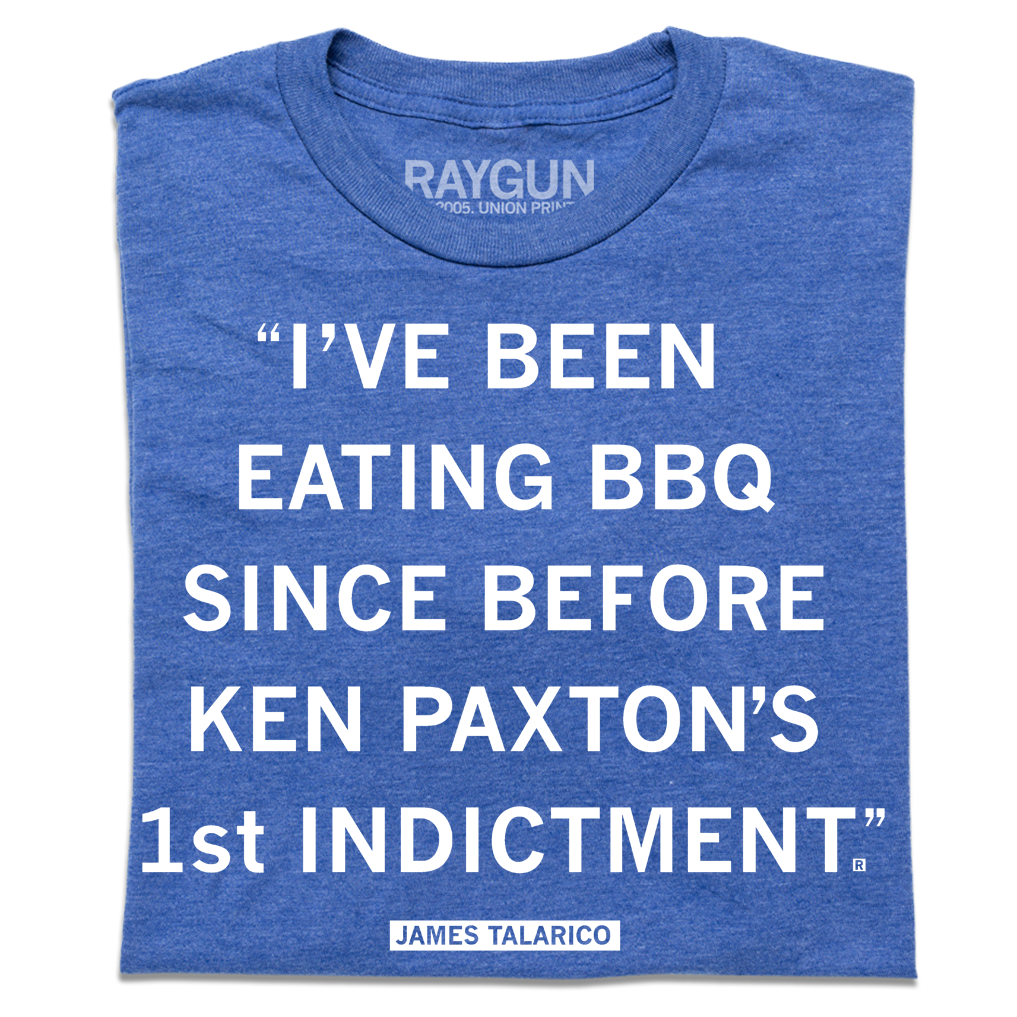 A folded heather blue shirt with white text that reads ""I've been eating BBQ since before Ken Paxton's 1st indictment." - James Talarico"