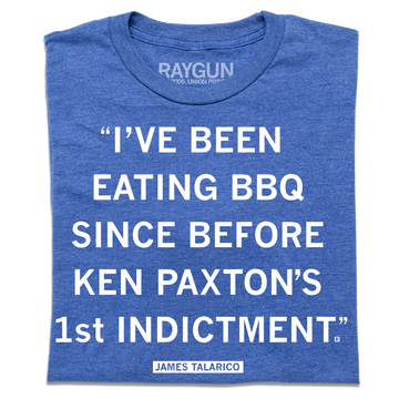 A folded heather blue shirt with white text that reads ""I've been eating BBQ since before Ken Paxton's 1st indictment." - James Talarico"