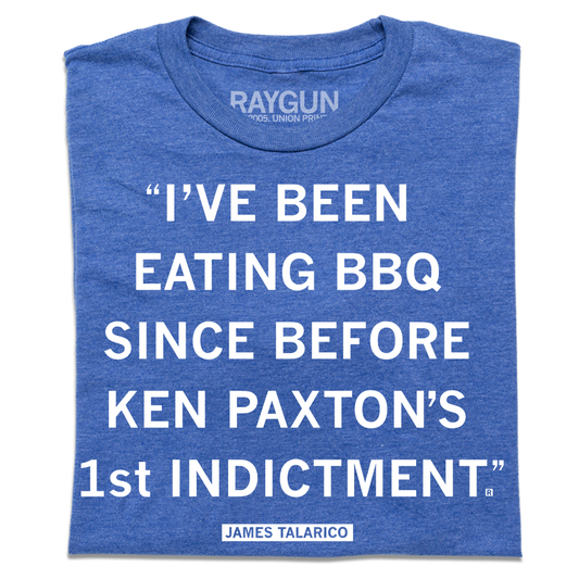 A folded heather blue shirt with white text that reads ""I've been eating BBQ since before Ken Paxton's 1st indictment." - James Talarico"