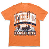 A burnt orange heavyweight t-shirt with navy and white ink. Text from the top to the bottom reads "The one, the only, The Netherlands meets Kansas City. World Cup 2026, Missouri." In the center is an illustration depicting notable places from The Netherlands and Kansas City mixed together.