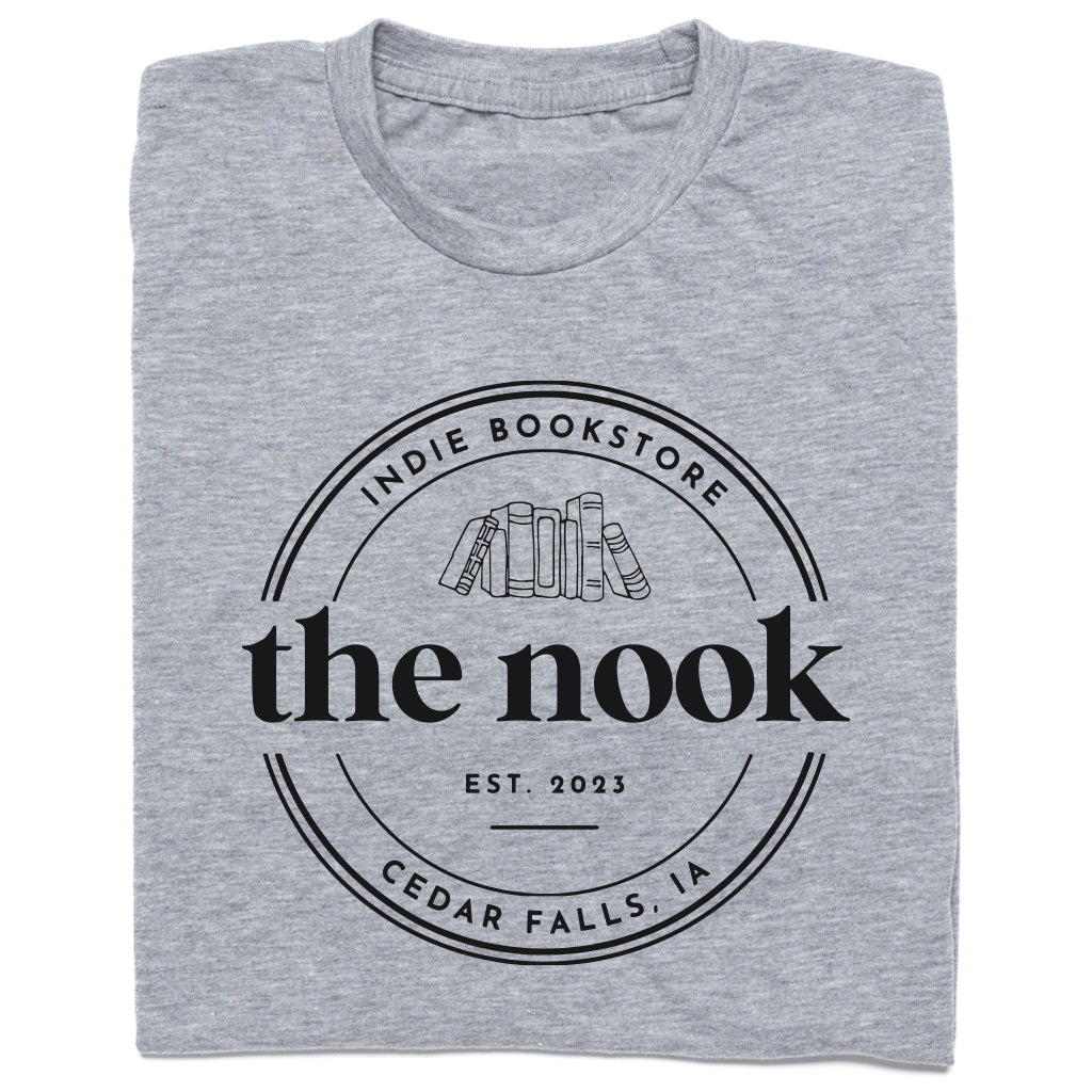 Heather grey t-shirt featuring a circular logo for The Nook, a Cedar Falls, IA indie bookstore, with the text Est. 2023 above an illustration of a row of books.