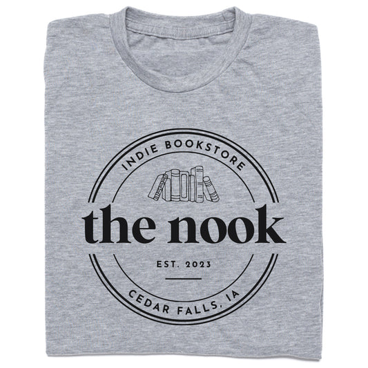 Heather grey t-shirt featuring a circular logo for The Nook, a Cedar Falls, IA indie bookstore, with the text Est. 2023 above an illustration of a row of books.