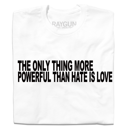 A folded white t-shirt with all caps black text that reads "The only thing more powerful than hate is love"