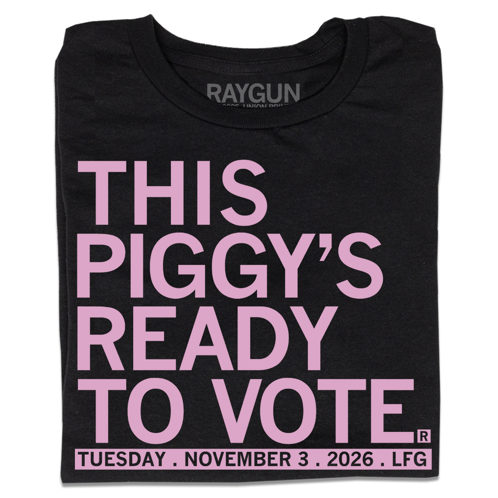 Folded black t-shirt with light pink ink that says, "This piggy's ready to vote. Tuesday, November 3rd 2026. LFG!"