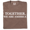 A brown, garment-dyed heavyweight crewneck t-shirt with the text TOGETHER, WE ARE AMERICA printed in white on the front.