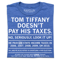 A folded heather royal blue t-shirt with centered white ink text that gets smaller every sentence. It says, "Tom Tiffany Doesn't Pay His Taxes. No, seriously, look it up! He paid NO state income taxes in 2006, 2007, 2008, 2009, or 2010. Oh, and he also voted to overturn a fair election. He does like talking about wolves though. Yup, that's also true. Trust me, this shirt is all facts."