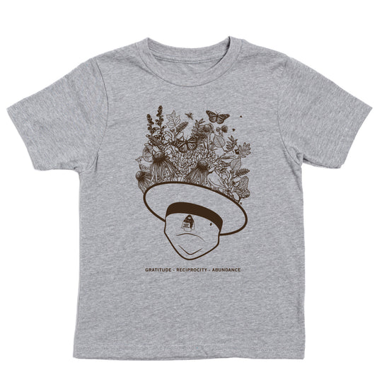 Gray union made t-shirt featuring a line-art illustration of a person wearing a wide-brimmed hat overflowing with flowers, leaves, and butterflies, with the words GRATITUDE - RECIPROCITY - ABUNDANCE printed below.