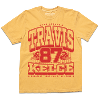 A Yellow shirt with red ink that reads "The Archer. Travis Kelce. The Greatest Tight End Of All Time" over an illustration of a football field  with the number 87 and a football helmet on either side.