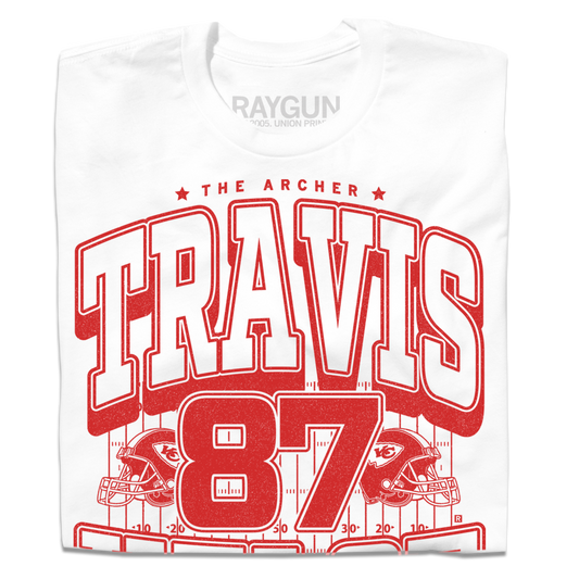 Folded white shirt with bright red ink that reads "The Archer. Travis Kelce. The Greatest Tight End Of All Time" over an illustration of a football field  with the number 87 and a football helmet on either side.