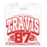 Folded white shirt with bright red ink that reads "The Archer. Travis Kelce. The Greatest Tight End Of All Time" over an illustration of a football field  with the number 87 and a football helmet on either side.